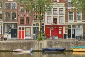 canal d'amsterdam avec maisons hollandaises typiques et péniches