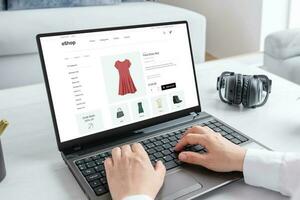 femme achat une étourdissant rouge robe en ligne avec portable ordinateur. moderne commerce électronique la toile page interface photo