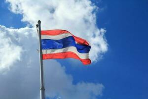 le thaïlandais drapeau cette est soufflé une façon par le vent avec le bleu ciel Contexte et des nuages dans le milieu de le chaud Soleil et fort vent. photo