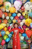 content femme portant ao dai vietnamien robe avec coloré lanternes, voyageur tourisme à salut un ancien ville dans central vietnam.landmark pour touristique attractions.vietnam et sud-est Voyage concept photo