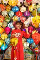 content femme portant ao dai vietnamien robe avec coloré lanternes, voyageur tourisme à salut un ancien ville dans central vietnam.landmark pour touristique attractions.vietnam et sud-est Voyage concept photo