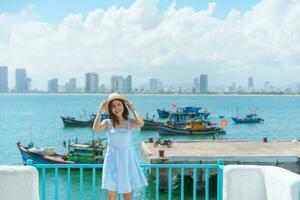 femme voyageur visite à fils tra Marina. touristique avec bleu robe et chapeau en voyageant dans da nang ville. vietnam et sud-est Asie Voyage concept photo