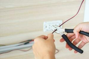 l'électricien coupe les fils électriques avec des pinces, l'installation des câbles de câblage pour la prise de courant. réparation, rénovation, réparation, service et développement de concepts de maisons et d'appartements photo