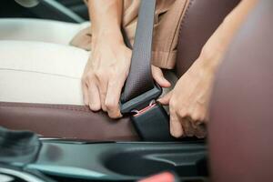 femme conductrice main attachant la ceinture de sécurité pendant qu'elle est assise à l'intérieur d'une voiture et conduit sur la route. concept de sécurité, de voyage, de voyage et de transport photo