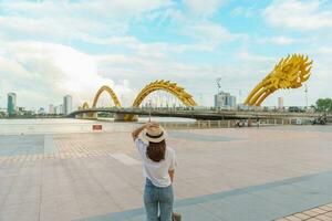 femme voyageur visite dans da nang ville. touristique tourisme le rivière vue avec dragon pont. point de repère et populaire pour touristique attraction. vietnam et sud-est Asie Voyage concept photo