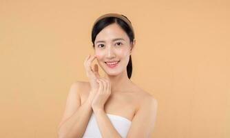 magnifique fille asiatique modèle émouvant Frais embrasé hydraté faciale peau sur beige Contexte fermer. beauté visage Jeune femme avec Naturel maquillage et en bonne santé peau portrait. peau se soucier concept photo