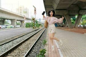 Jeune asiatique femme voyageur sauter à côté de chemin de fer train station dans Bangkok. périple voyage mode de vie, monde Voyage explorateur ou Asie été tourisme concept. photo