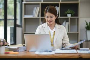 femme d'affaires asiatique utilisant un ordinateur portable et travaillant au bureau avec un document de calculatrice sur le bureau, faisant la planification en analysant le rapport financier, l'investissement dans le plan d'affaires, le concept d'analyse financière. photo