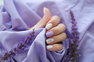 aux femmes mains avec branché très péri manucure et fleurs dans violet. mains avec printemps été violet carré clous. photo