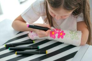 une peu fille des peintures une jeter sur sa bras. une enfant dessine une dessin sur une jeter après une main blessure. photo