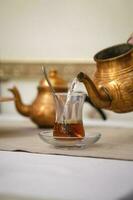 une homme main verse thé dans une turc tasse de une cuivre théière. photo