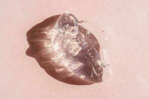 transparent cosmétique gel sur une rose Contexte. photo