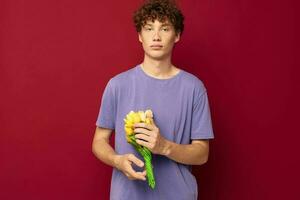 mignonne adolescent en portant une Jaune bouquet de fleurs violet t-shirts rouge Contexte inchangé photo