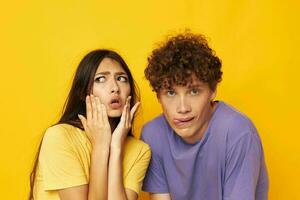 Jeune garçon et fille dans coloré t-shirts posant relation amicale amusement Jaune Contexte inchangé photo