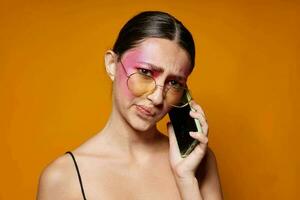 Jeune magnifique femme avec une téléphone dans main brillant maquillage posant mode émotions Jaune Contexte inchangé photo