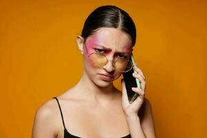 portrait de magnifique Jeune femme avec une téléphone dans main brillant maquillage posant mode émotions fermer inchangé photo