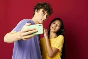 agréable gars et fille dans coloré t-shirts avec une téléphone rouge Contexte photo