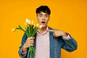 Jeune gars dans denim veste avec une bouquet de fleurs posant romance photo