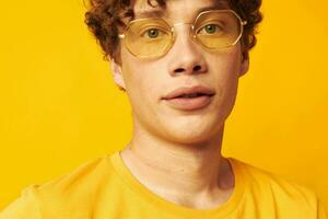 gars avec rouge frisé cheveux Jaune T-shirt des lunettes mode main gestes mode de vie inchangé photo