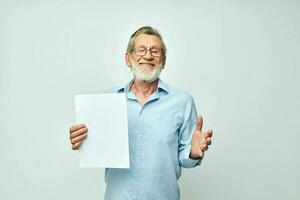 Sénior aux cheveux gris homme en portant une feuille de papier copie-espace posant isolé Contexte photo