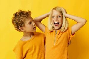 deux joyeux les enfants dans Jaune t-shirts permanent côté par côté enfance émotions Jaune Contexte photo
