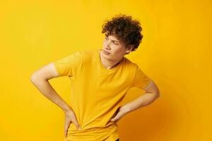 portrait de une Jeune frisé homme portant élégant Jaune T-shirt posant Jaune Contexte inchangé photo