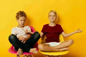 deux joyeux les enfants enfance séance sur chaises ensemble sur coloré Contexte photo