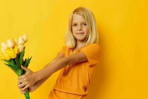 mignonne peu fille avec blond cheveux une bouquet de Jaune fleurs photo
