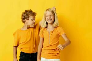 mignonne préscolaire des gamins dans Jaune t-shirts permanent côté par côté enfance émotions Jaune Contexte photo