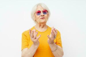 souriant personnes âgées femme dans une Jaune T-shirt posant lumière Contexte photo