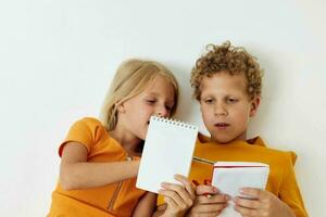 petit les enfants mensonge sur le sol avec blocs-notes et des crayons isolé Contexte inchangé photo