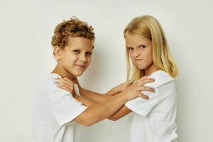 peu garçon et fille dans blanc t-shirts sont permanent suivant à mode de vie inchangé photo