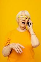 souriant personnes âgées femme content mode de vie dans Jaune t-shirts avec téléphone fermer émotions photo