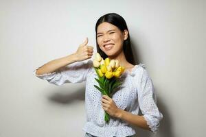 femme avec asiatique apparence dans une blanc chemise fleurs printemps posant lumière Contexte inchangé photo