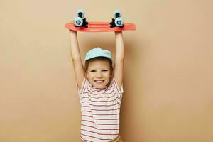 mignonne fille planche à roulette dans main posant bébé vêtements amusement isolé Contexte photo