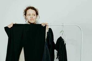 jolie femme dans une costume gestes avec le sien mains garde-robe lumière Contexte inchangé photo