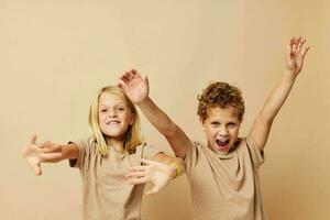 peu garçon et fille dans beige t-shirts posant pour amusement enfance inchangé photo