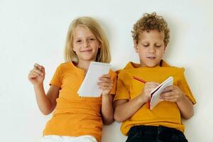 deux joyeux les enfants mensonge sur le sol avec blocs-notes et des crayons enfance mode de vie inchangé photo