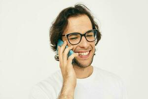 attrayant homme dans une blanc T-shirt la communication par téléphone lumière Contexte photo