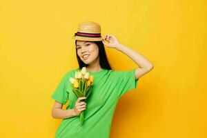 jolie brunette vert T-shirt une bouquet de Jaune fleurs dans une chapeau isolé Contexte inchangé photo