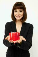 portrait de une femme avec cadeau petit boîte dans une cuir costume noir veste isolé Contexte photo