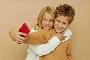 portrait de mignonne les enfants étreinte divertissement selfie posant relation amicale beige Contexte photo