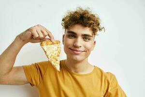 attrayant homme dans une Jaune T-shirt en mangeant Pizza mode de vie inchangé photo