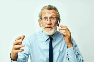 vieux homme avec téléphone dans studio sur blanc Contexte parlant photo