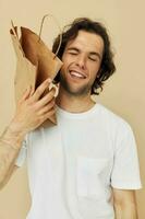 Beau homme dans une blanc T-shirt avec papier sac isolé Contexte photo