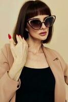attrayant femme dans des lunettes de soleil court aux cheveux costume faire des gestes avec mains lumière Contexte photo