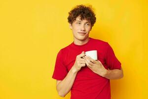 gars avec rouge frisé cheveux dans une rouge T-shirt avec une blanc casquette dans le sien mains isolé Contexte inchangé photo