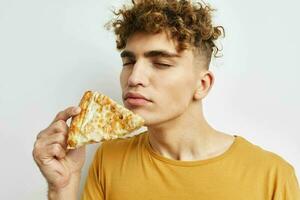 Beau gars en mangeant Pizza posant fermer lumière Contexte photo