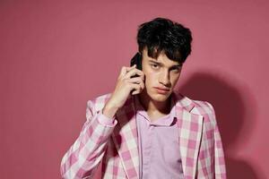 Beau gars avec une téléphone dans main rose blazer mode élégant style modèle studio photo