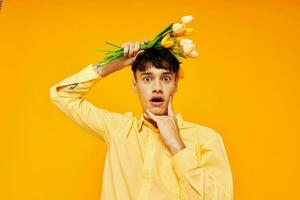 une Jeune homme avec une à la mode coiffure dans Jaune chemises avec fleurs Jaune Contexte inchangé photo